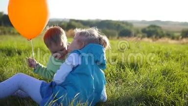 快乐的孩子们在公园里玩耍。 男孩拥抱并亲吻他的妹妹。 气球。 孩子们的笑声和微笑